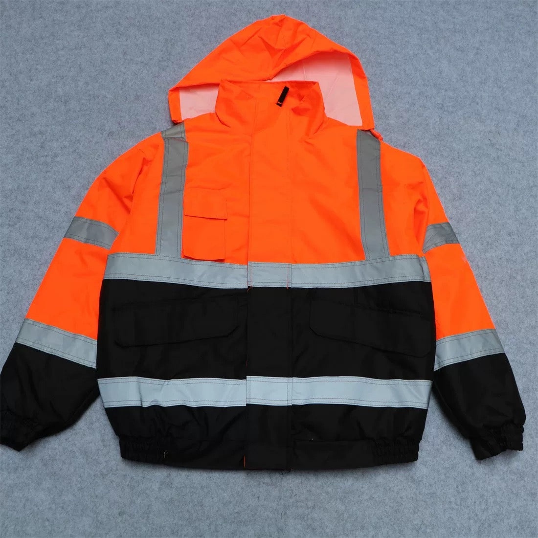 Custom orange hi-vis padded safety work jacket with reflective strips, flat lay view showing full design and color.